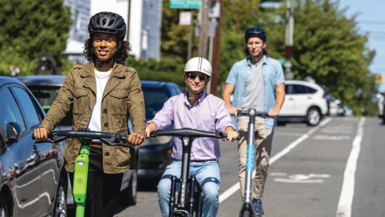 People riding e-bikes and scooters in a NYC bike lane with helmets on.