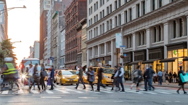 Fast paced street scene with people walking across a busy intersection on Broadway in Manhattan New York City