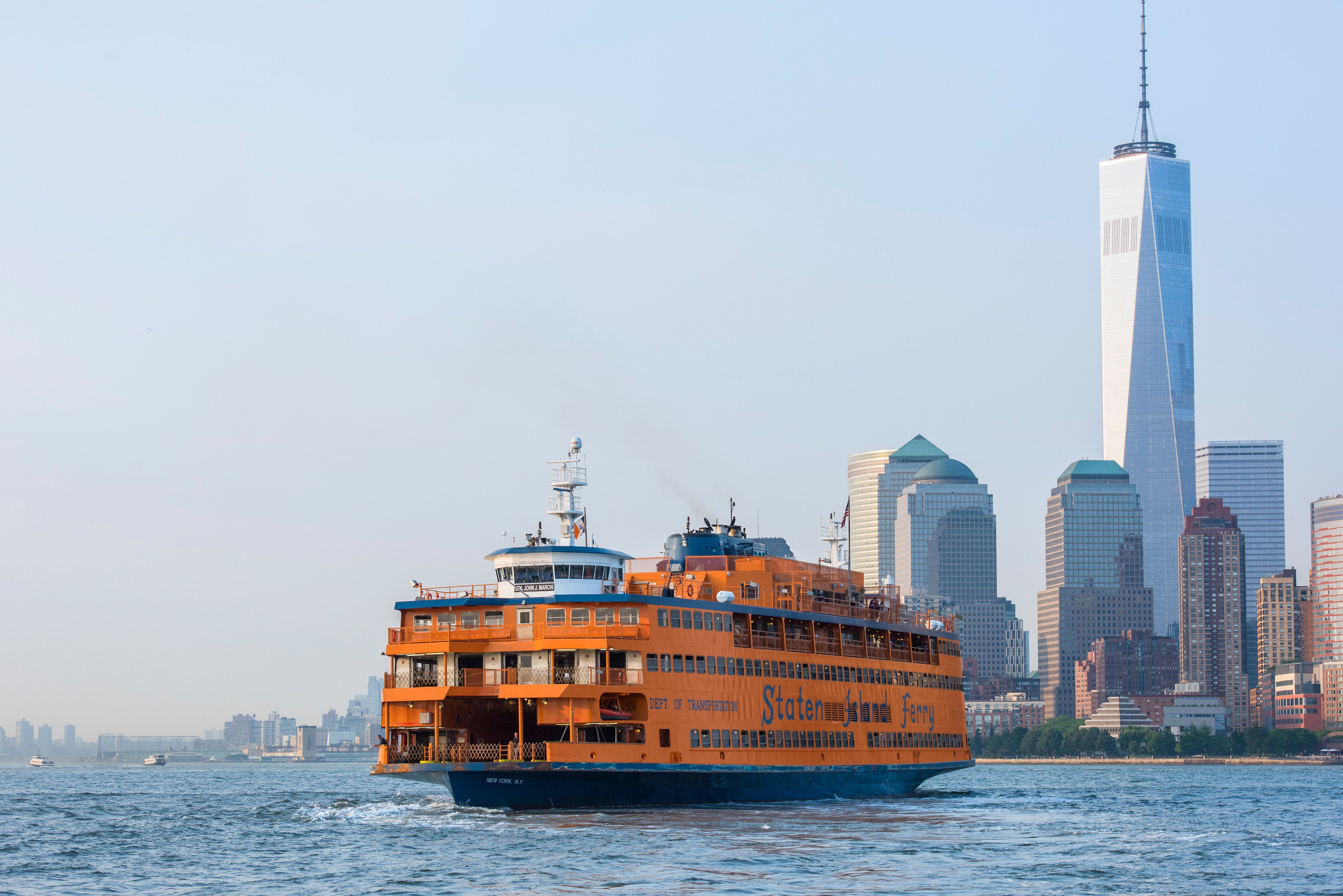 Staten Island Ferry sails across the water with the New York City skyline, including One World Trade Center, visible in the background on a clear day. Photo by Julienne Schaer/ NYC and Company.