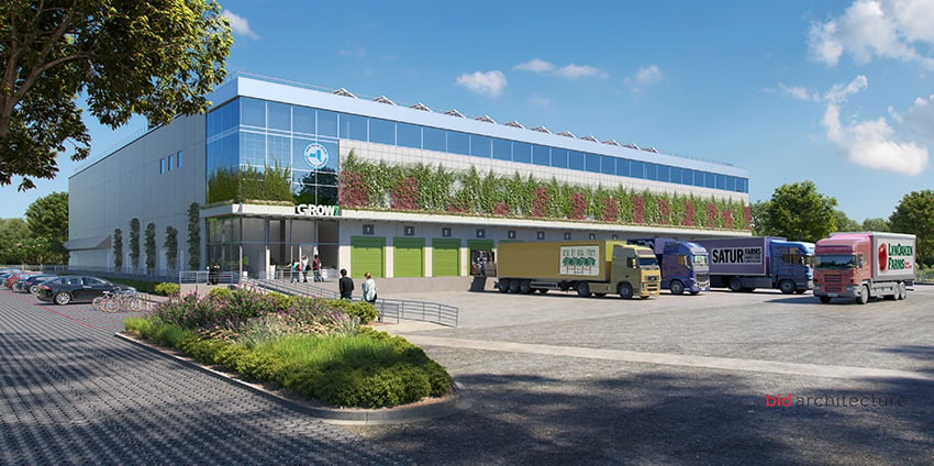 Rendering of GrowNYC Bronx Point Food Distribution Center shows a modern distribution center with a green rooftop, large windows, and loading docks. Several colorful trucks are parked outside, and people walk near the entrance. Trees and bikes line the foreground under a blue sky. Credit: bld Architecture.