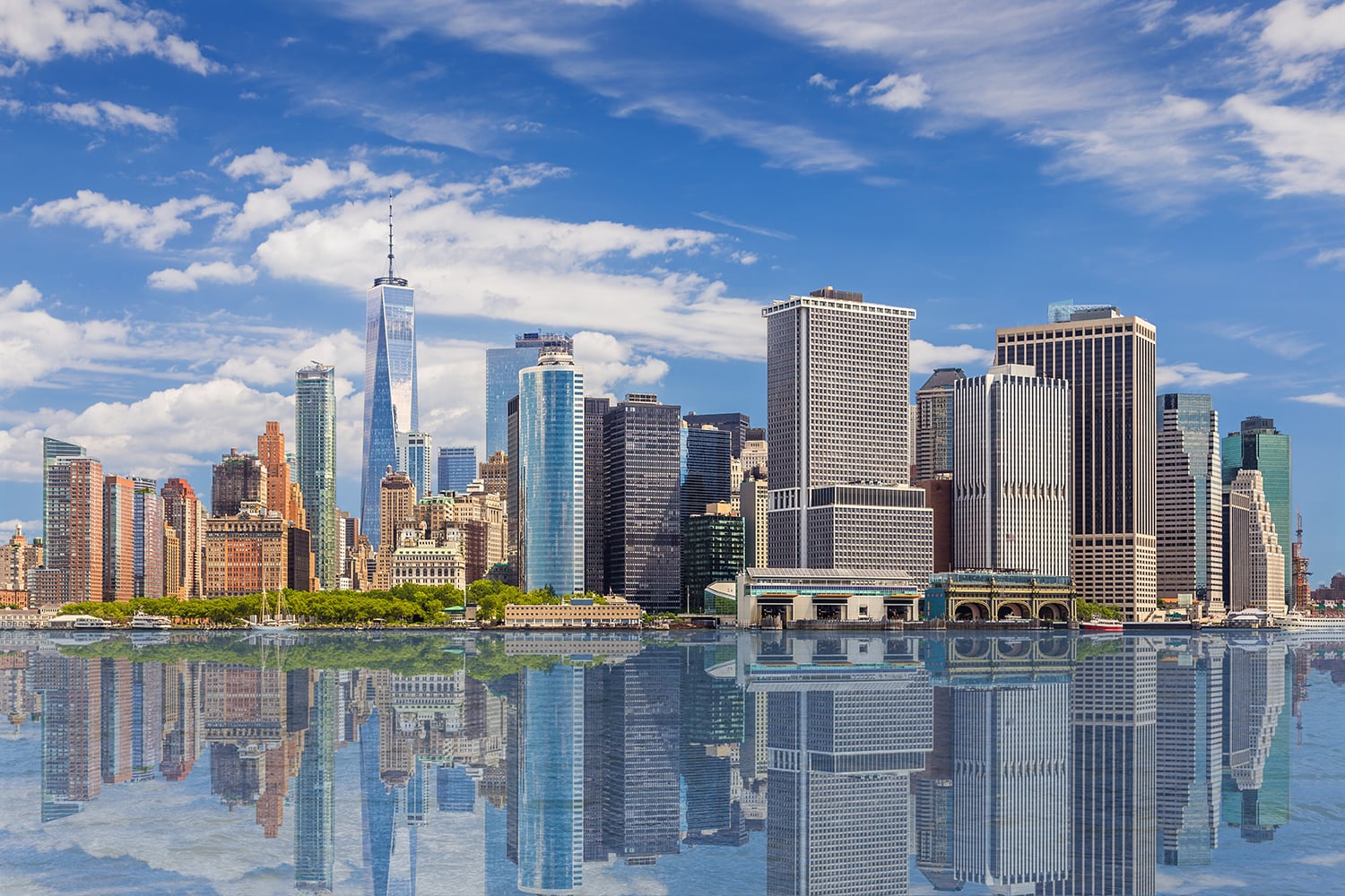 New York City skyline with Financial District and World Trade Center reflected in water of New York Harbor.