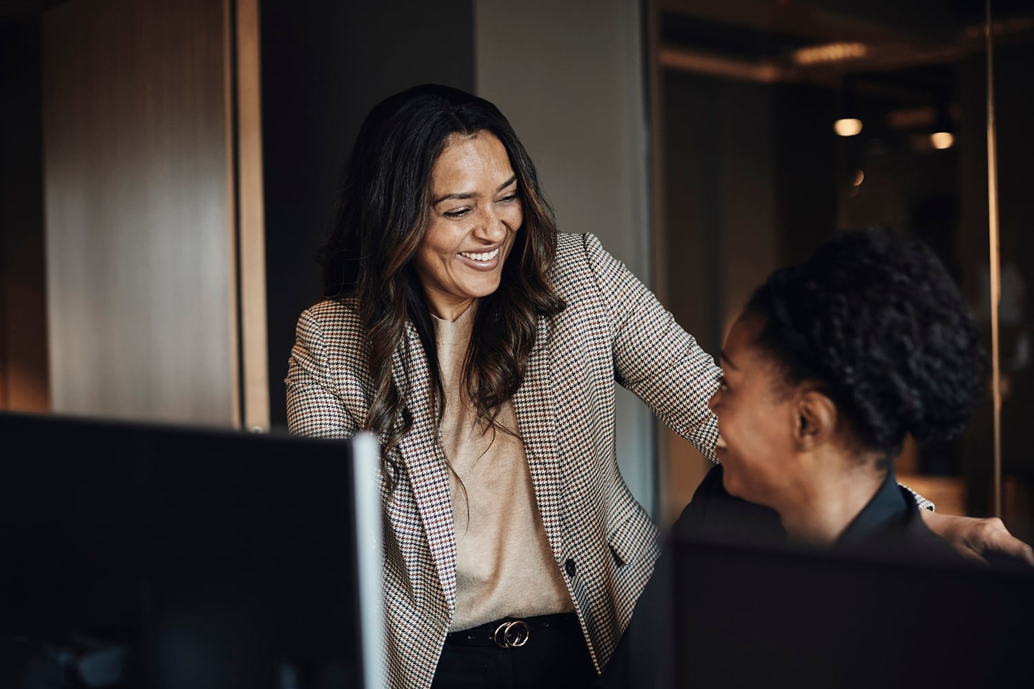 Two happy female business colleagues communicating with each other.