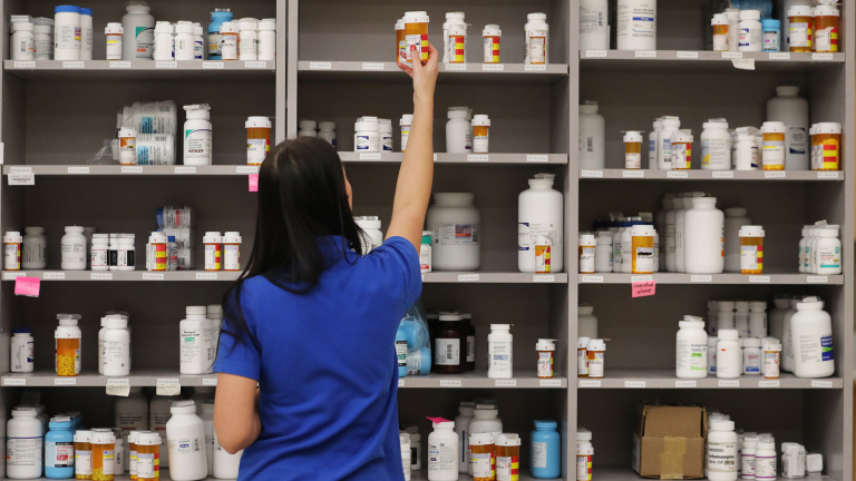 Show thumbnail preview A person in a blue shirt reaches for a prescription bottle on a shelf in a pharmacy. The shelves are filled with various bottles of medication. Show thumbnail preview A person in a blue shirt reaches for a prescription bottle on a shelf in a pharmacy. The shelves are filled with various bottles of medication.