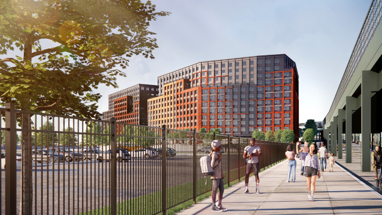 Conceptual Rendering of Willets Point housing. A modern urban scene with people walking on a sidewalk next to a fence. Two large, multistory buildings with red and brown facades are visible. A tree provides greenery, and a blue sky is above. A parking area is partially visible.