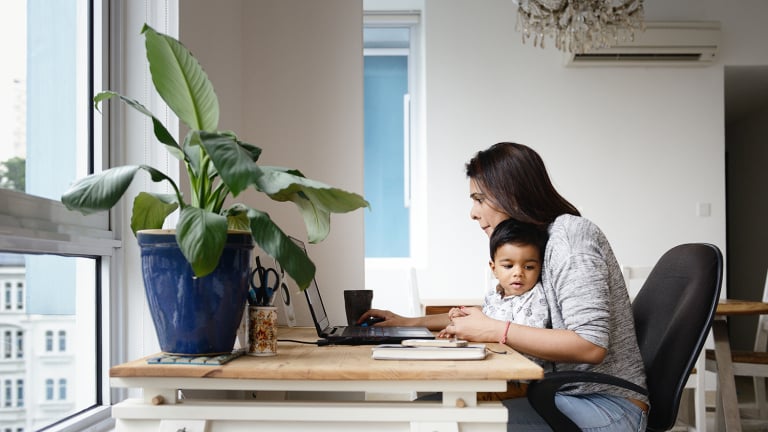 Woman working from a home office desk with her son.