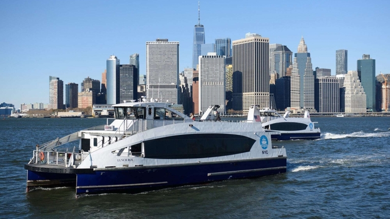 Two NYC Ferries crossing in front of Downtown NYC