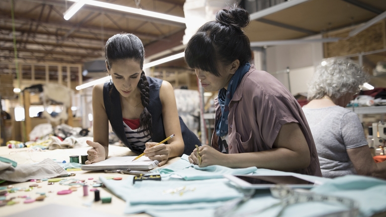 Three fashion designers working at a studio space