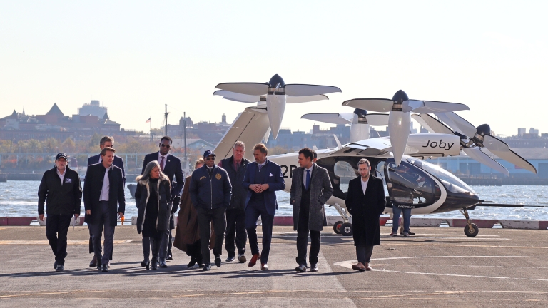 NYC Mayor Adams and leaders walking in front of an electric vertical take-off and landing (eVTOL) aircraft. NYC Mayor Adams and leaders walking in front of an electric vertical take-off and landing (eVTOL) aircraft.