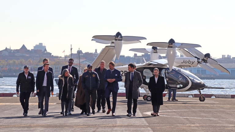 NYC Mayor Adams and leaders walking in front of an electric vertical take-off and landing (eVTOL) aircraft.