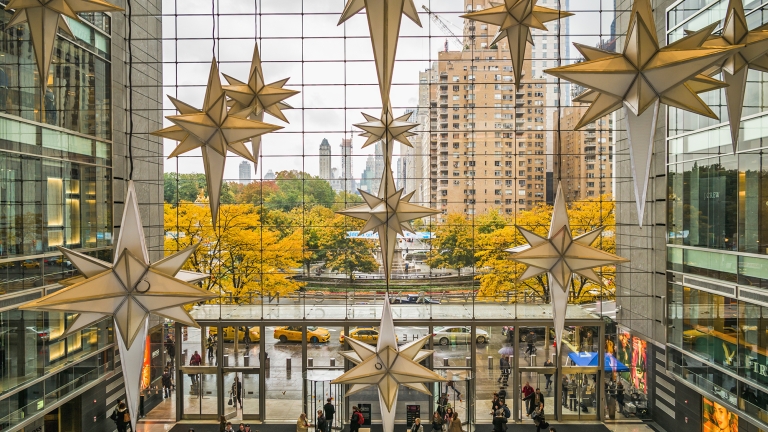 Holiday decorations in the Shops at Columbus Circle with a view of the fountain and trees through the glass façade.