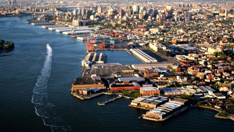 Aerial view of Brooklyn waterfront with Red Hook in foreground and East river in background.