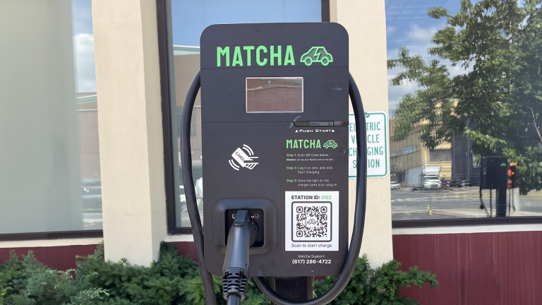 Matcha Electric vehicle charging station with a QR code for starting a charge, and a plugged-in charging cable, outside of the Brooklyn Army Terminal.