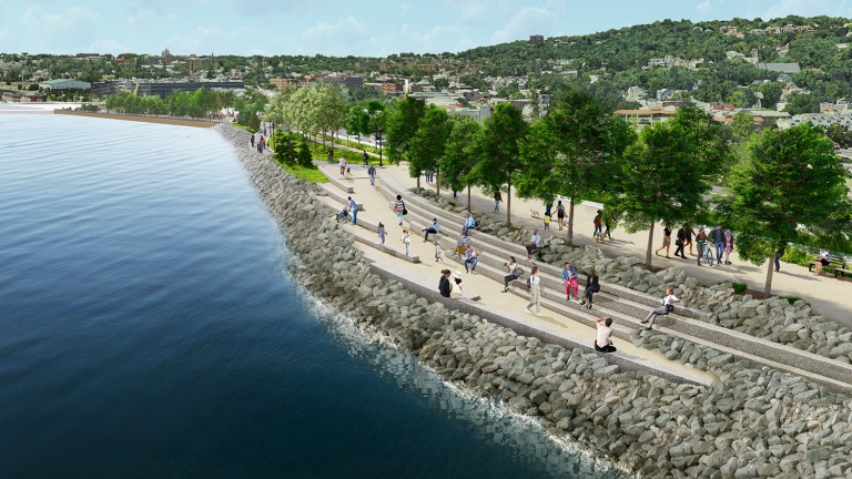 Rendering of people walking and relaxing on a tree-lined new stapleton waterfront esplanade beside a rocky shore, with a view of New York City and hills in the background.