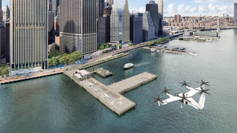Aerial rendering of downtown manhattan heliport with a flying air taxi above water, surrounded by New York City skyscrapers and a ferry at the dock. Aerial rendering of downtown manhattan heliport with a flying air taxi above water, surrounded by New York City skyscrapers and a ferry at the dock.