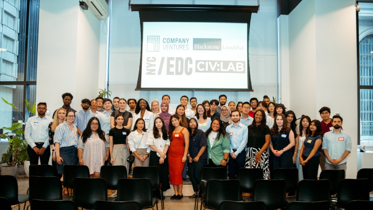 A diverse group of interns from NYC Startup Internship Program pose for a group photo in front of a screen displaying logos for Company Ventures, Blackstone, LaunchPad, NYCEDC, and CIV:LAB. They are in a room with large windows and potted plants.