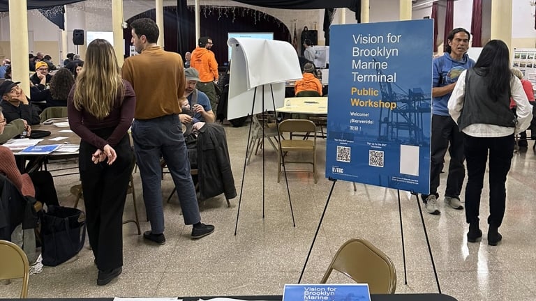 People are gathered in a community center for a public workshop about the Brooklyn Marine Terminal. A signboard provides event details. Some people are seated while others stand and discuss near a presentation easel. The atmosphere is collaborative. People are gathered in a community center for a public workshop about the Brooklyn Marine Terminal. A signboard provides event details. Some people are seated while others stand and discuss near a presentation easel. The atmosphere is collaborative.