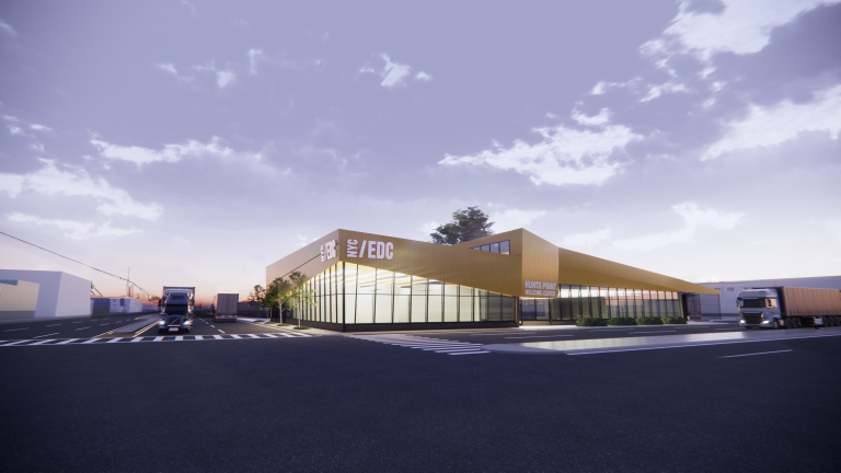 Rendering by Dattner Architects showing a modern, angular building with large glass windows and yellow accents sits beside a wide road. Trucks are parked nearby, and the sky is partly cloudy during sunset or sunrise. The building is labeled NYC/EDC. Rendering by Dattner Architects showing a modern, angular building with large glass windows and yellow accents sits beside a wide road. Trucks are parked nearby, and the sky is partly cloudy during sunset or sunrise. The building is labeled NYC/EDC.