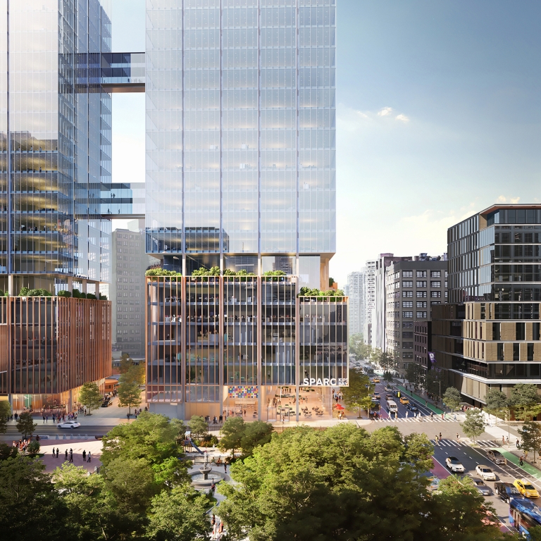 Aerial rendering of SPARC Kips Bay. A modern New York City scape with tall glass skyscrapers reflecting sunlight. The buildings are surrounded by trees and busy streets filled with cars and people. Balconies with greenery are visible. The word SPARC is on one of the buildings.