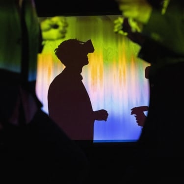 Side view of businessperson watching through virtual reality glasses in exhibition center.