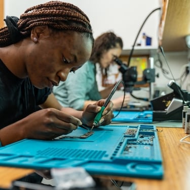 Technicians repairing broken smartphone on desk.