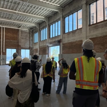 NYCEDC interns and fellows taking a tour through the MADE Bush Terminal Campus, with their helmets on.