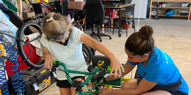 Child being helped with getting on adaptive bike. Photo: Adapt Ability.