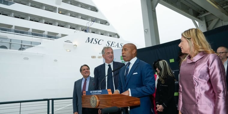 Mayor Adams speaks from behind podium in front of cruise ship