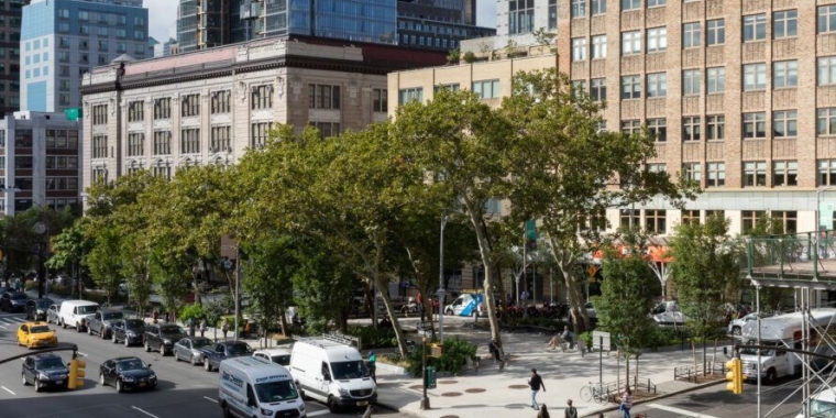 Corner of Hudson Square with tall trees amongst buildings