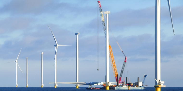 Construction of offshore wind farm. Crane ship is preparing for lifting up rotor of the wind turbine.