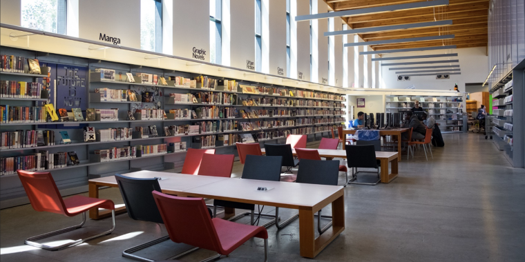 Chairs and desks with shelves of books in the West New Brighton Library.