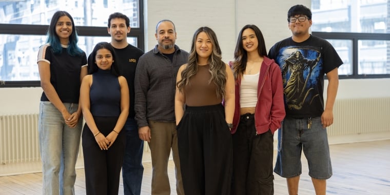 Makelab Co-Founders and staff stand together inside Makelab space on a light wooden floor, smiling at the camera. They are casually dressed, and large windows with NYC views are in the background.
