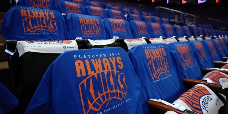 Rows of arena seats with blue T-shirts draped over them, each featuring the text PLAYOFFS 2026 ALWAYS KNICKS Eastern Conference Finals in orange and white letters. Photo by Sarah Stier/Getty Images.