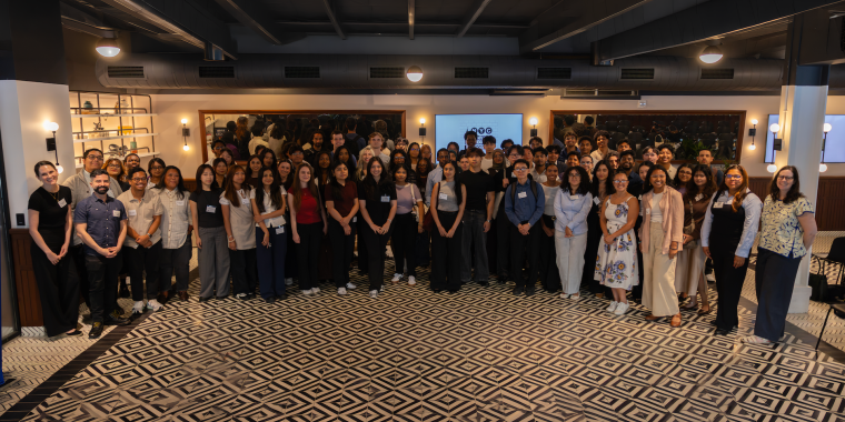 Startup and Venture Capital 2026 intern cohort pose for a photo in a spacious, modern room with patterned flooring, ceiling lights, and shelves in the background.