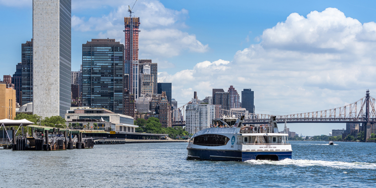 View from the East River Esplanade near Stuyvesant Cove featuring a ferry boat with the United Nations Building in the background. 
