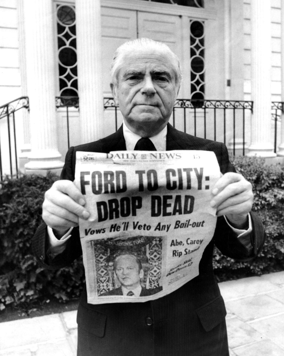  “Ford to City: Drop Dead” was the famous headline that ran on October 30th, 1975 in the New York Daily News, as shown here held by Abraham Beame, Mayor of New York City from 1974-1977. Image: Getty Images.