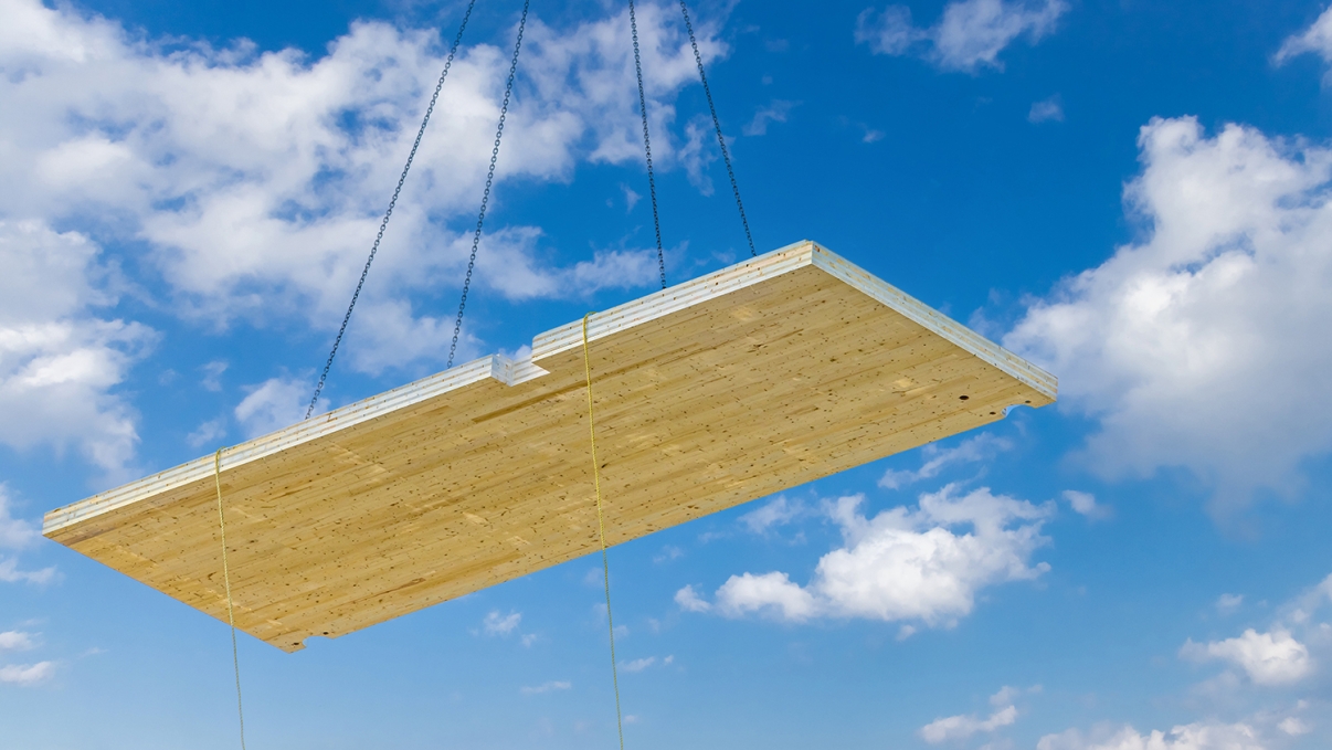 Engineered wood suspended in air from a crane, blue sky in background