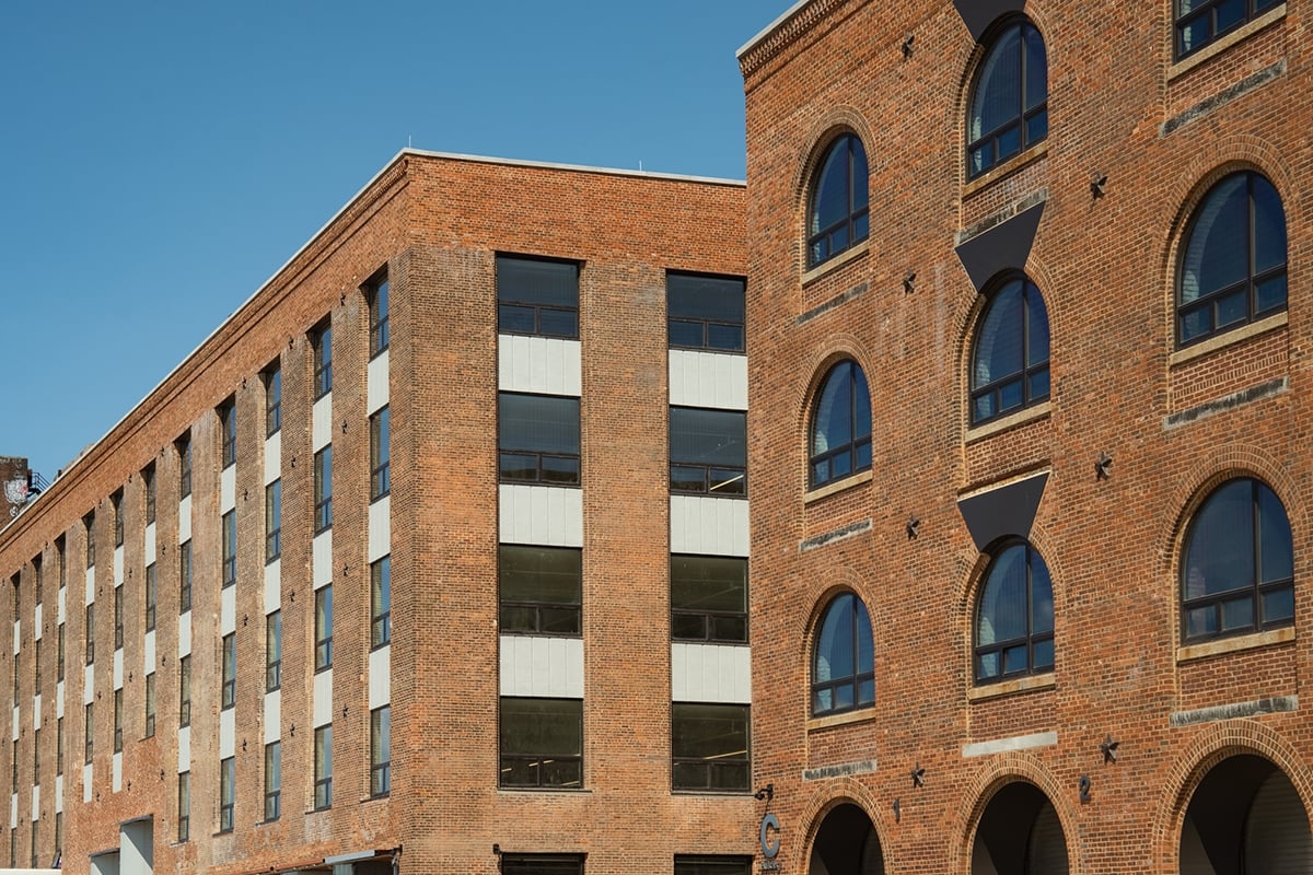 Two brick buildings with arched and rectangular windows against a clear blue sky. Two brick buildings with arched and rectangular windows against a clear blue sky.