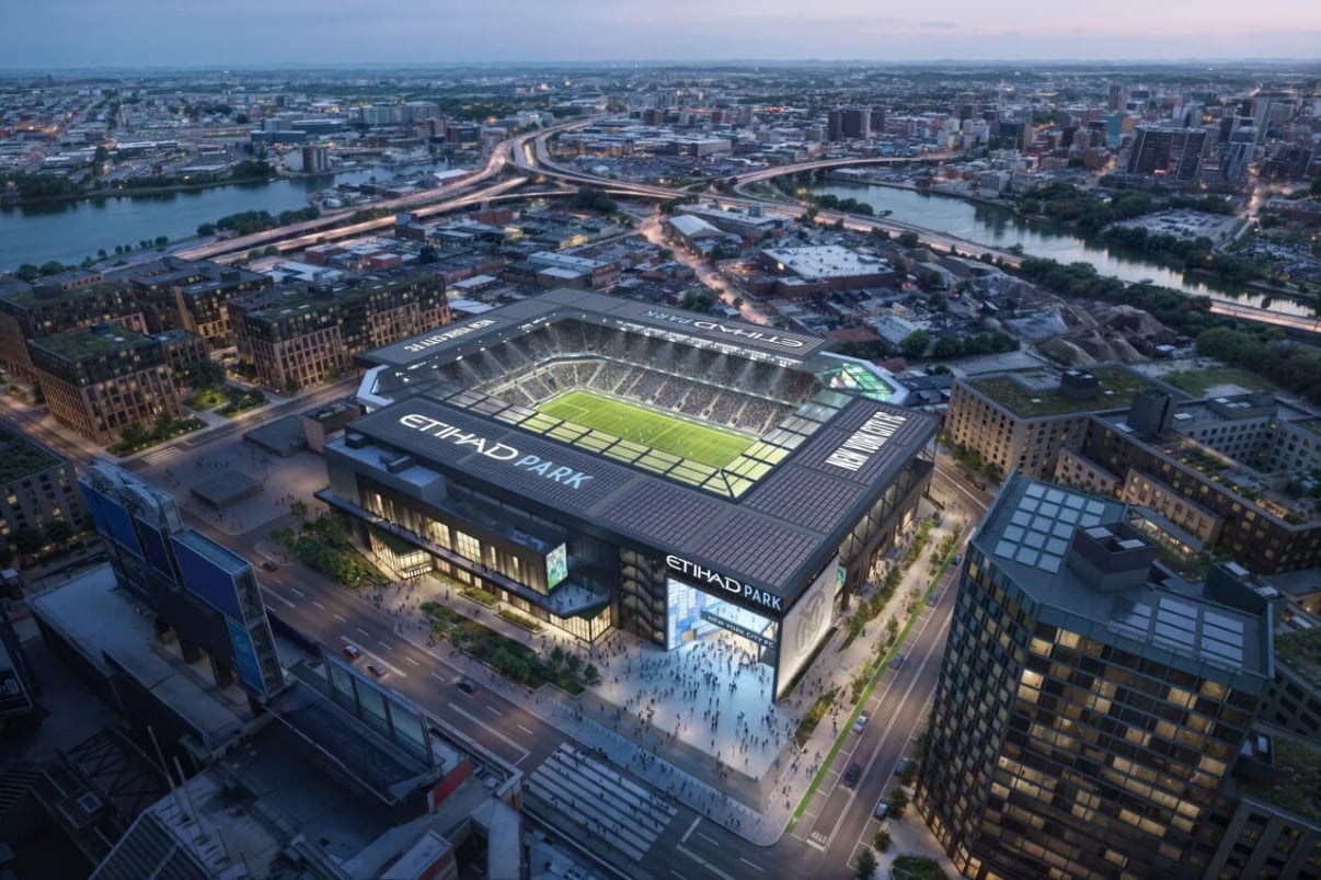 Aerial view of a football stadium labeled &quot;Etihad Park&quot; surrounded by urban landscape, with roads and a river in the background.