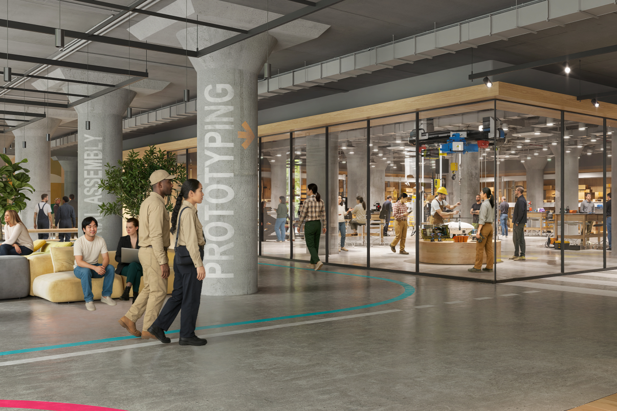 Interior rendering of BATWorks shows a modern, open-concept workspace with groups of people collaborating, lounge seating, glass-walled meeting rooms, and large labeled columns reading ASSEMBLY and PROTOTYPING. Some people are working, walking, or talking.