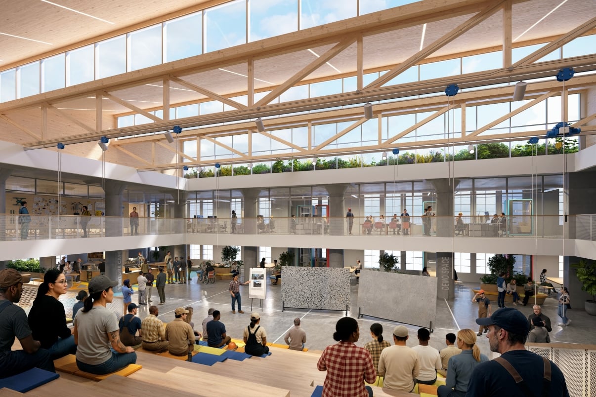 BATWorks interior rendering features a spacious, modern atrium with exposed wooden beams, large windows, and two floors. People are gathered, some seated on tiered benches and others mingling or viewing displays on the ground floor.