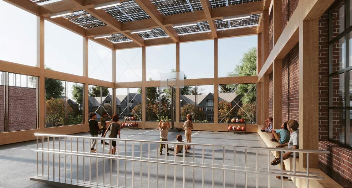 Interior render of Ganeinu Academy shows children playing basketball in a modern indoor gym with large windows, wooden beams, solar panels on the roof, and natural light. Adults and kids sit on benches along the brick walls, watching the game.