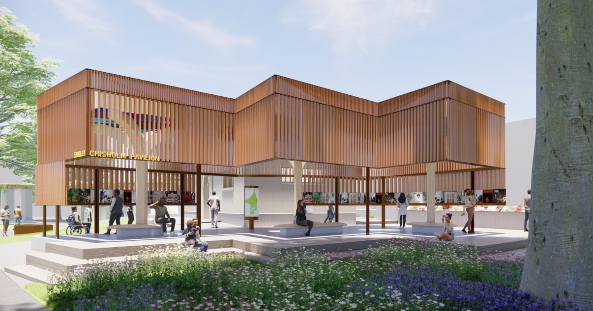 Exterior render of a modern pavilion with wooden slats and open sides stands in a park. People sit and walk around the building, which is surrounded by greenery, flowers, and trees. The sign reads “Shirley Chisolm Pavilion.”