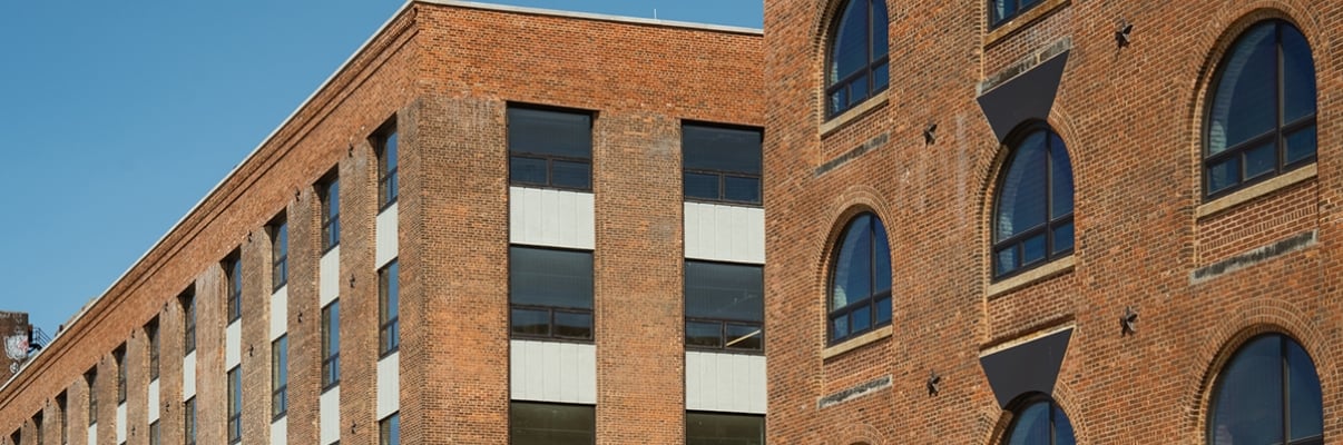 Two brick buildings with arched and rectangular windows against a clear blue sky. Two brick buildings with arched and rectangular windows against a clear blue sky.